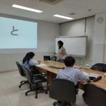 Seorang pengajar sedang memberikan pelatihan bahasa Jepang kepada dua karyawan industri dalam kelas khusus persiapan rotasi global ke Jepang.