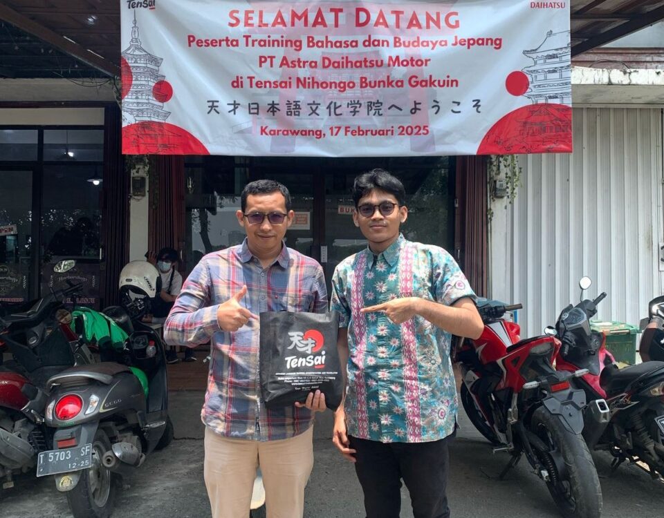 Dua peserta berfoto di depan banner penyambutan training bahasa dan budaya Jepang untuk PT Astra Daihatsu Motor di Tensai Indonesia, Karawang.