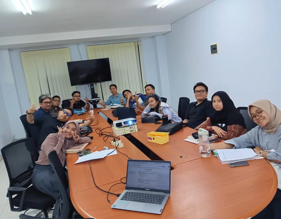 Peserta pelatihan bahasa Jepang in house duduk di ruang rapat, berpose santai bersama instruktur di tengah sesi pelatihan di perusahaan manufaktur.