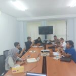 Peserta pelatihan bahasa Jepang on site duduk di ruang rapat perusahaan, mempelajari materi menggunakan ponsel dan buku pelajaran.