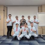 Peserta training bahasa Jepang di pabrik berfoto bersama instruktur setelah sesi pelatihan di lingkungan kerja manufaktur.