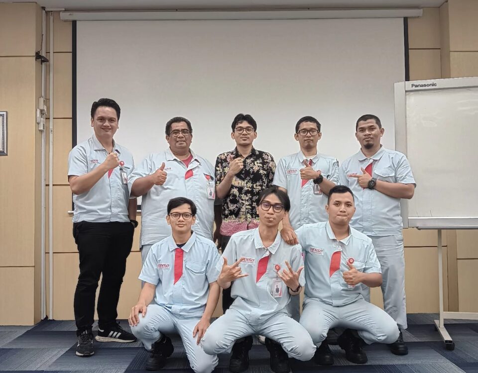 Peserta training bahasa Jepang di pabrik berfoto bersama instruktur setelah sesi pelatihan di lingkungan kerja manufaktur.