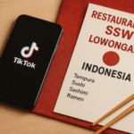 Digital fotografi realistik yang menampilkan suasana rekrutmen lowongan SSW restoran Jepang bagi WNI, dengan smartphone menampilkan aplikasi TikTok, di samping kartu menu rekrutmen bergaya Jepang di atas alas merah, tanpa kehadiran manusia, warna dominan kayu dan aksen merah.
