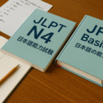 Fotografi realistik materi belajar untuk tes JLPT N4 dan JFT Basic: buku teks, catatan bahasa Jepang, pensil, dan lembar latihan ujian di atas meja kayu hangat dengan aksen merah. Gambar ini memvisualisasikan persiapan tes JLPT N4 JFT Basic kerja Jepang dengan nuansa modern dan unik.