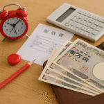 Foto realistik biaya hidup pekerja baru di Jepang: lembar uang 10.000 yen, kalkulator, struk belanja, jam meja merah, dan dompet kulit di atas meja kayu, menyimbolkan pengelolaan keuangan harian pekerja pendatang, tanpa kehadiran manusia, angle close-up yang unik.